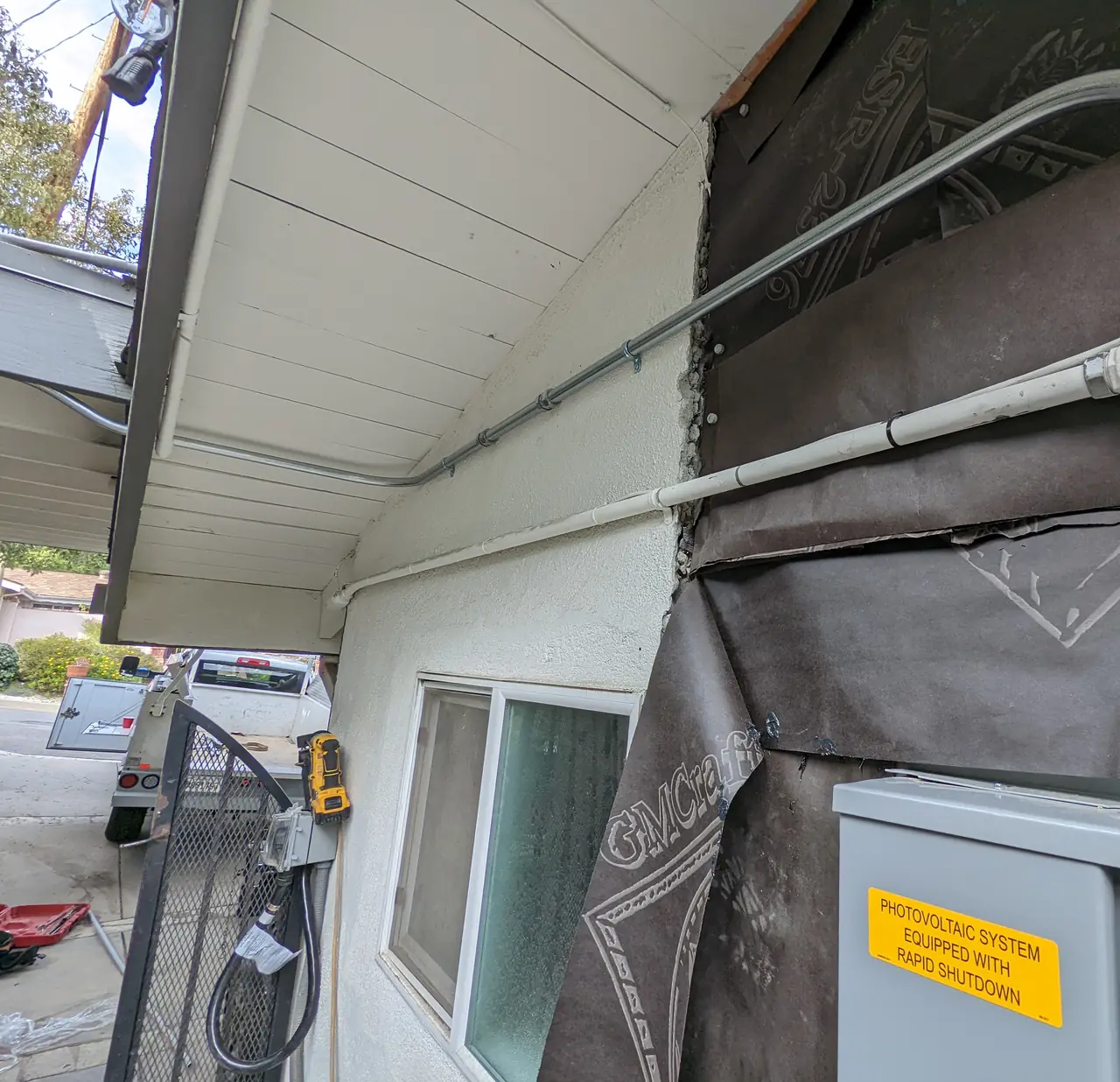 Conduit running along the underside of the eave with labeled electrical equipment on the wall, Woodland Hills