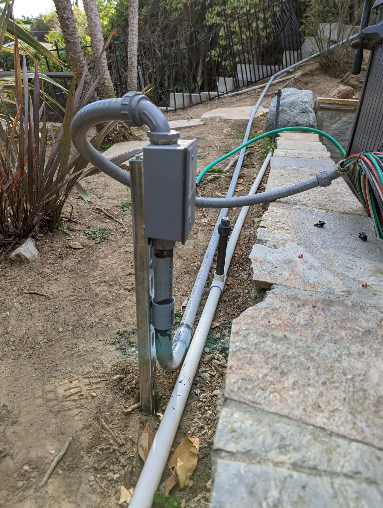 A closed weatherproof box on a post at the end of a conduit run beside the garden path, Woodland Hills