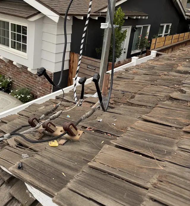 An aging wood shake roof with the electrical service mast rising straight through it, Woodland Hills