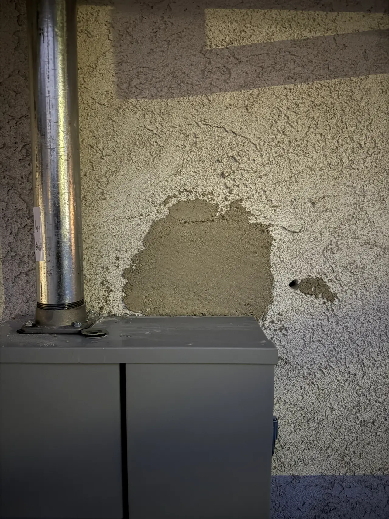 Freshly patched stucco beside new electrical equipment on an exterior wall, Woodland Hills