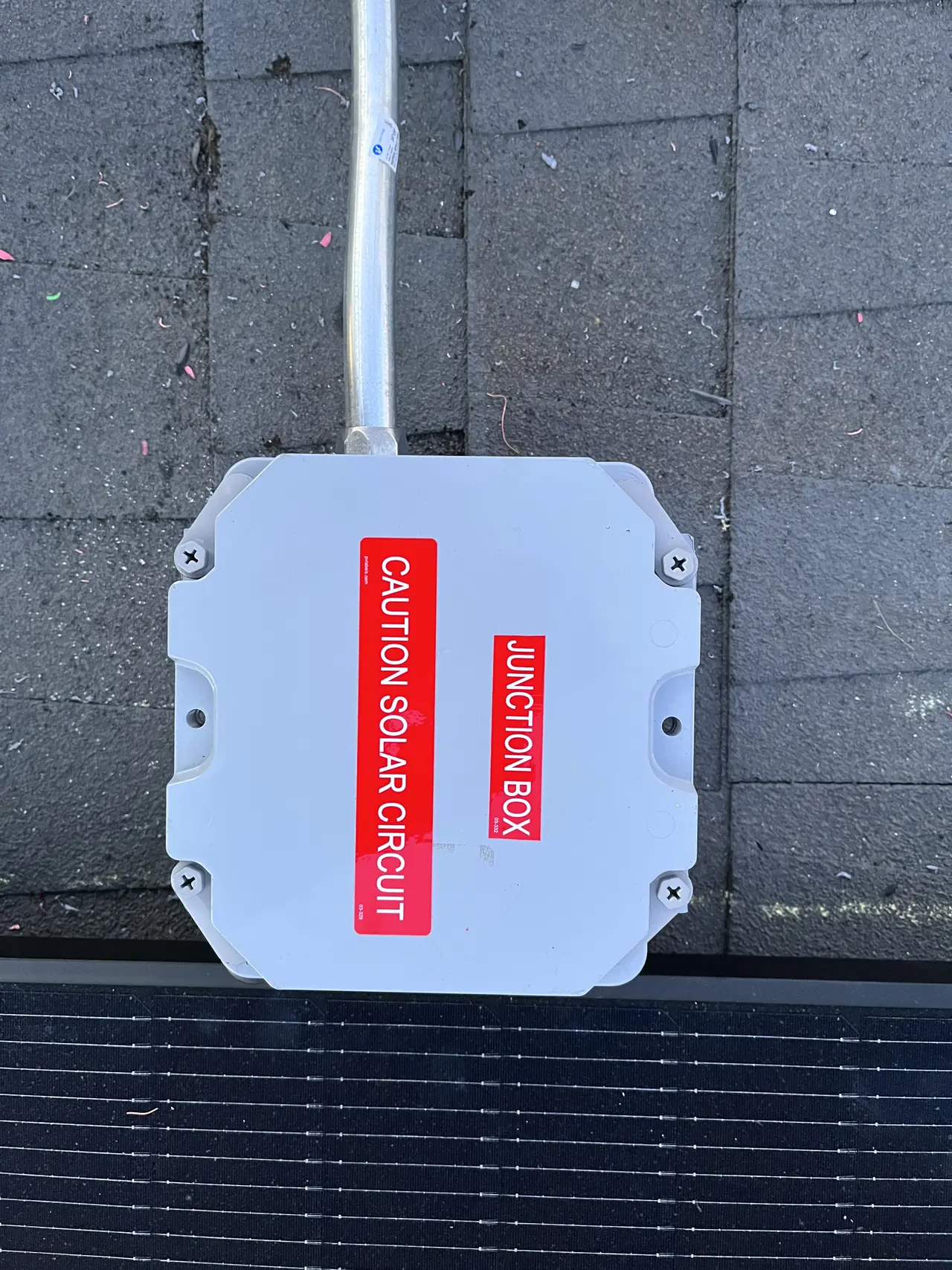 A closed junction box labeled as a solar circuit, mounted on the roof beside the edge of a module, Woodland Hills